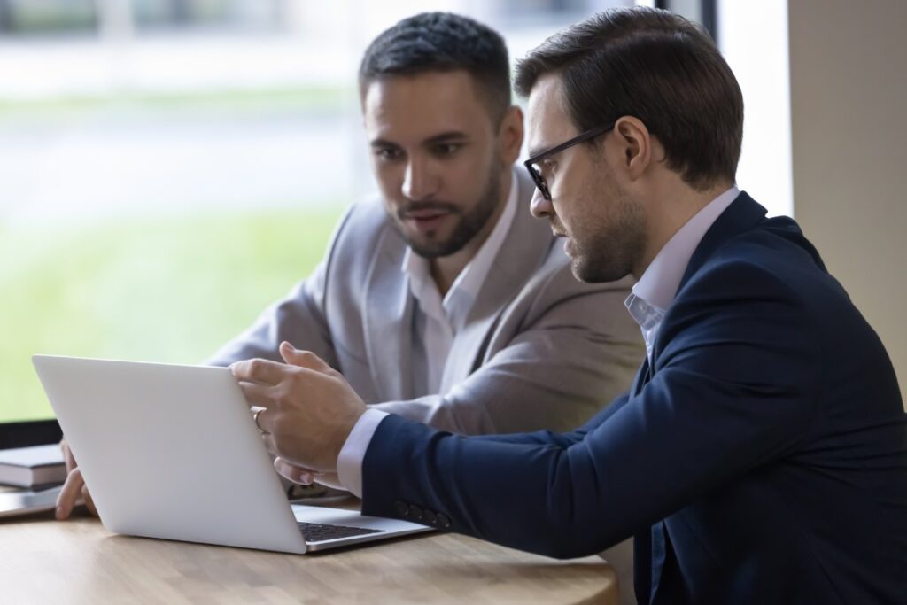 Two professionals look at a laptop screen