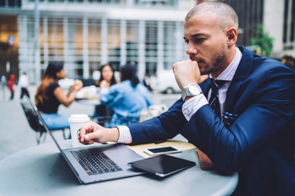 A business man works on a laptop at a public park