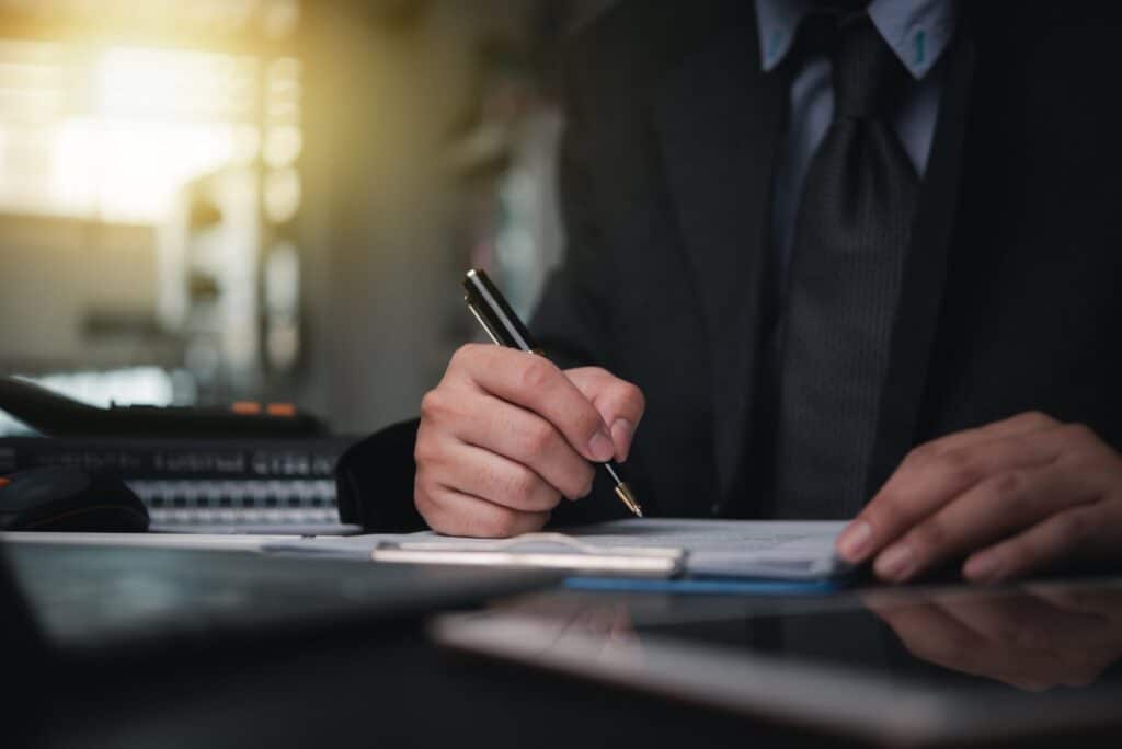 A person in a suit uses an executive-style pen to sign an intellectual property agreement.